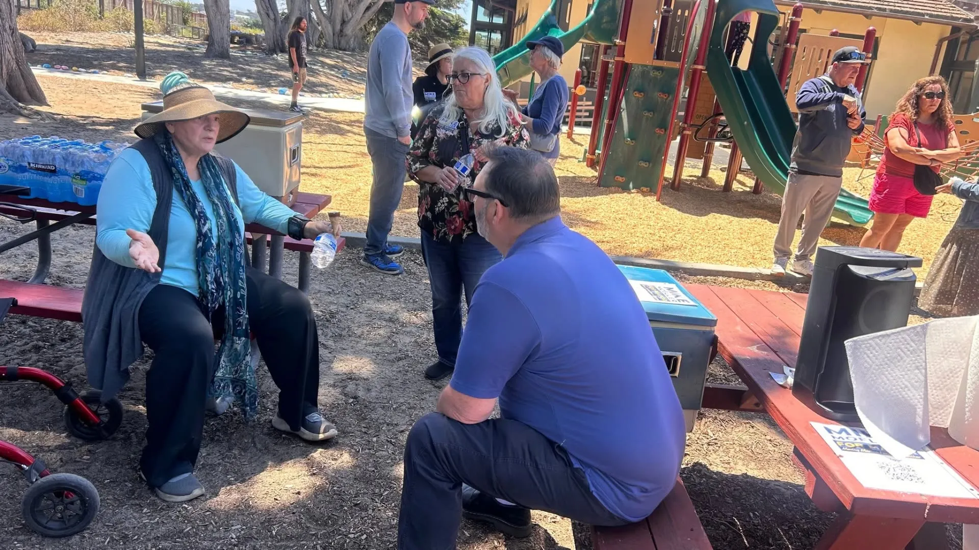 Mike Moeller crouching to talk with a resident at a community event in Marina