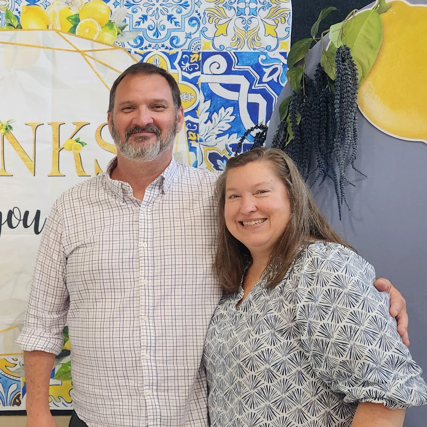 Mike and Cosette Moeller, smiling side by side in front of a lemon-print backdrop.
